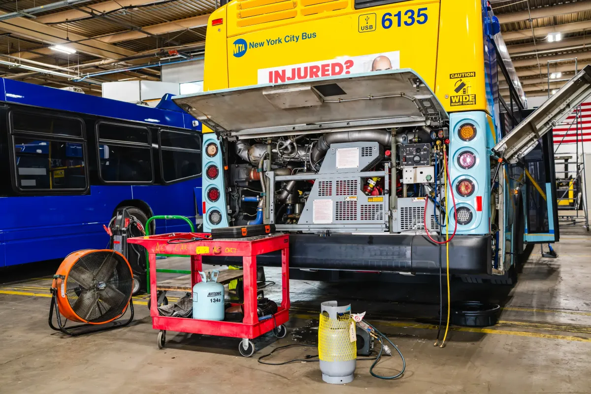 Hybrid electric bus with rear engine compartment open during maintenance inside NEBR facility