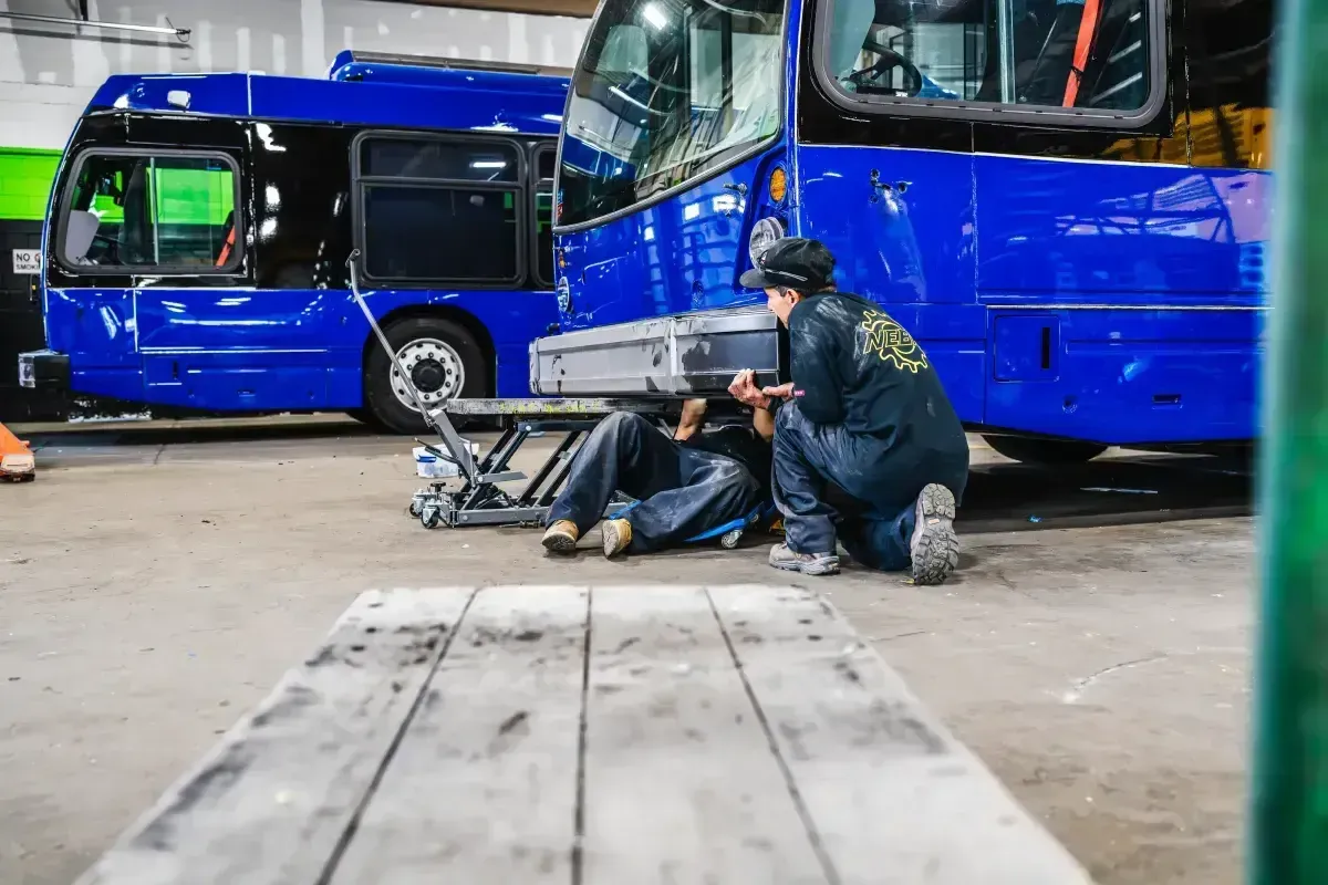 Technicians performing suspension system overhaul on a transit bus