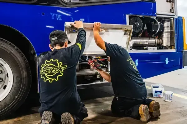 Diesel technicians performing engine maintenance on a transit bus