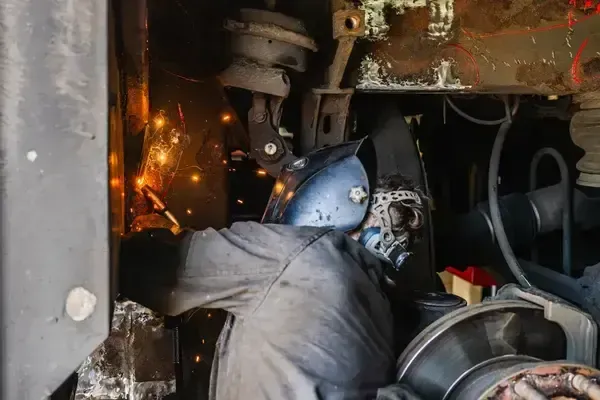 Technician welding inside bus frame at NEBR