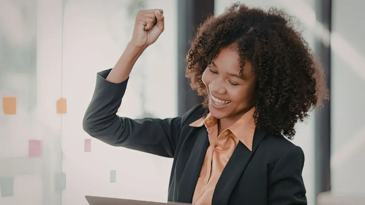 Confident Black professional woman celebrating success in the workplace, representing Black Freedom and Wellbeing: Reclaiming Rest and Joy through empowerment, resilience, leadership growth, and emotional wellbeing.