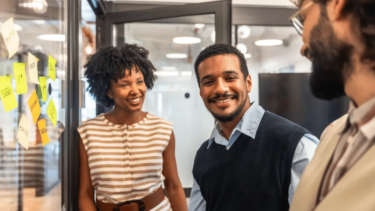 Image Description: A confident leader guiding a diverse team during a strategy meeting, standing beside a glass board with evolving plans. The atmosphere reflects optimism, adaptability, and teamwork in a modern workplace.