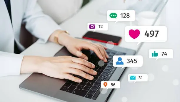 Person typing on a laptop with social media engagement notifications, illustrating social media management and audience interaction for brand presence.