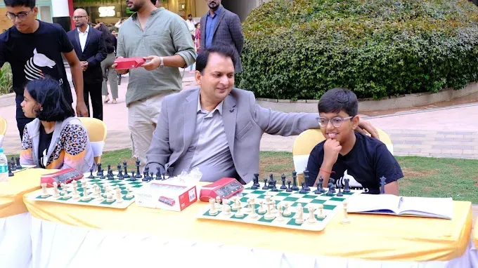 Chess coach guiding a young boy during a chess game at an outdoor event.