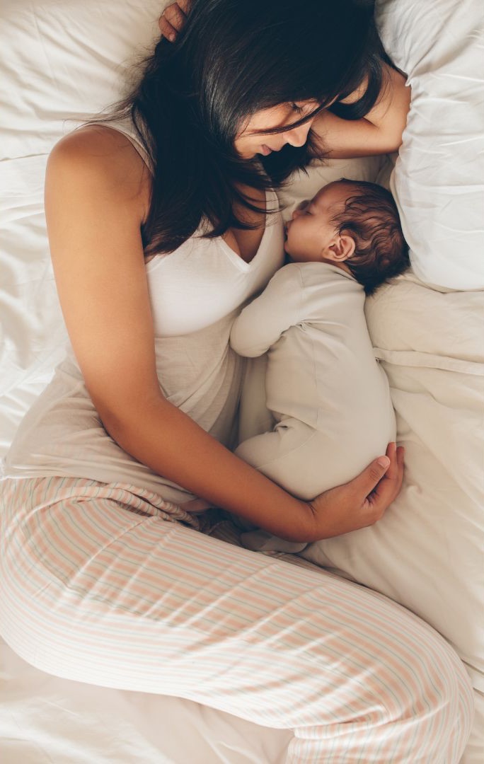 Smiling mother cradling her infant in a peaceful home setting, supported by postpartum doula services