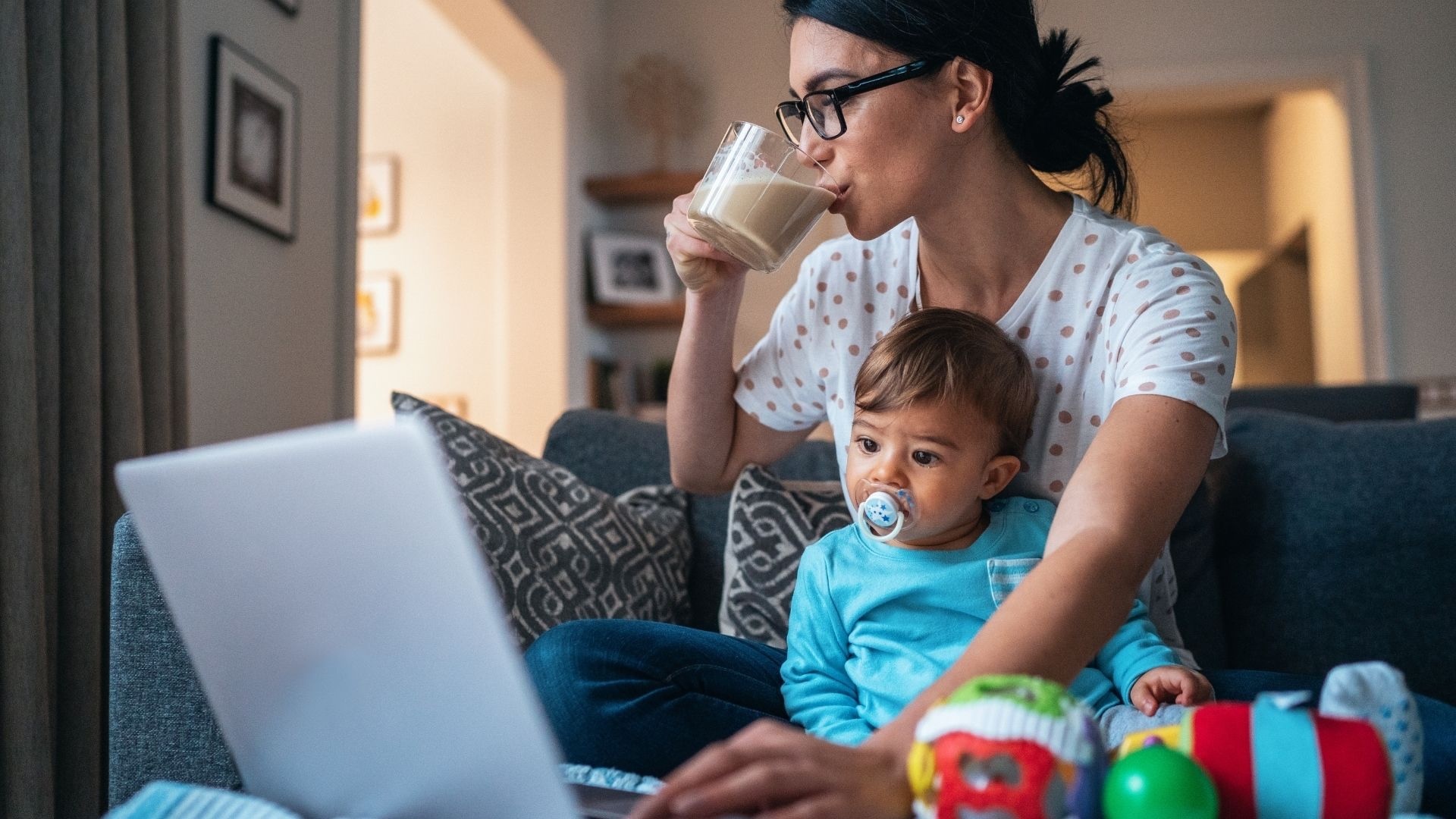 Mother on computer with toddler searching on computer to find online programs to be supported in her postpartum and motherhood journey