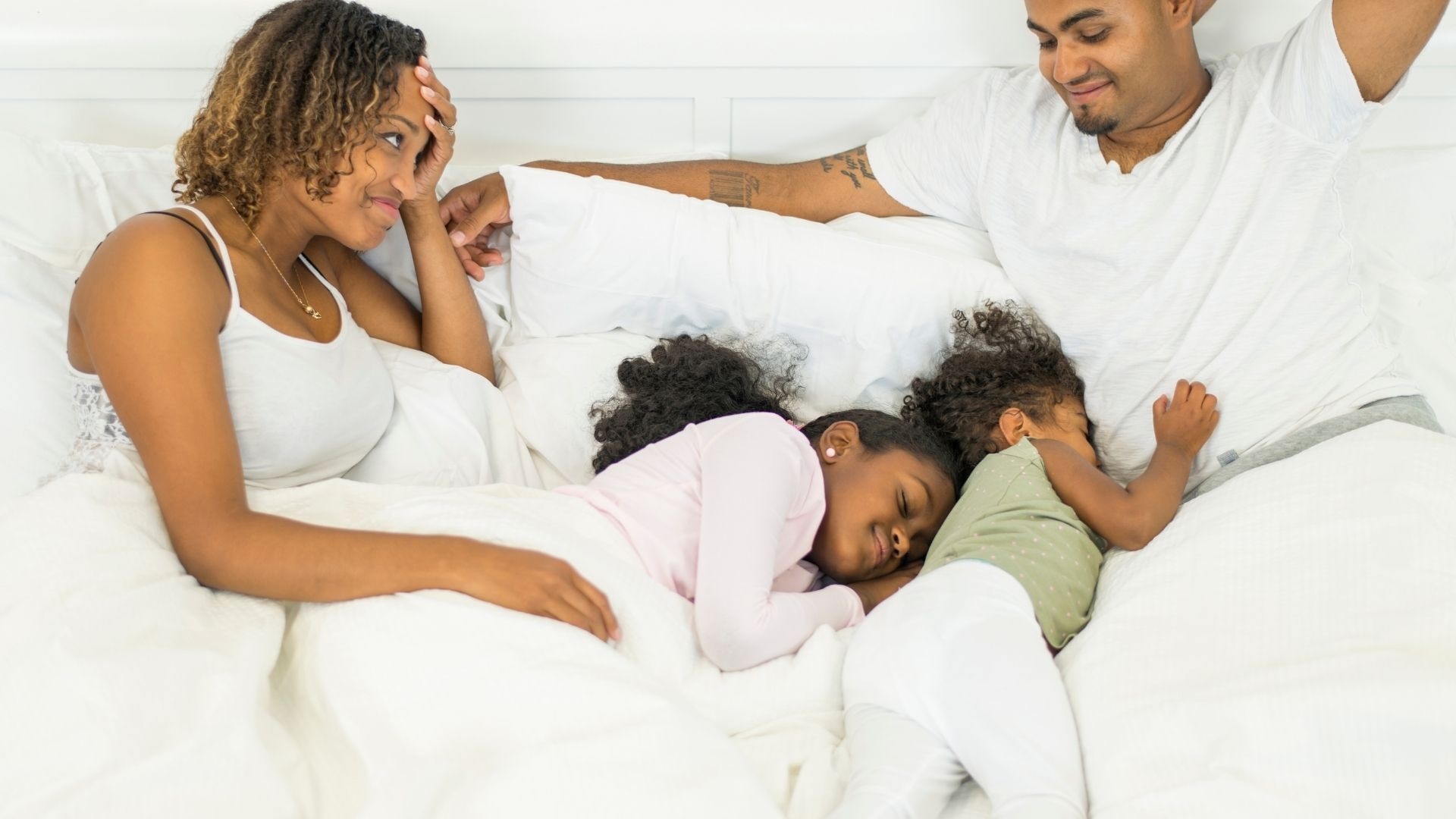 Peaceful family co-sleeping with their baby, resting together in a calm, softly lit bedroom.