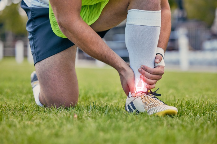 football player suffering from ankle pain during sport