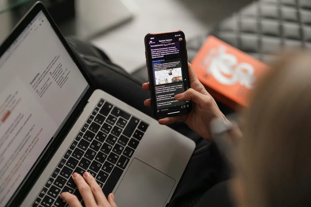 Person reading messages on a phone while working at a laptop