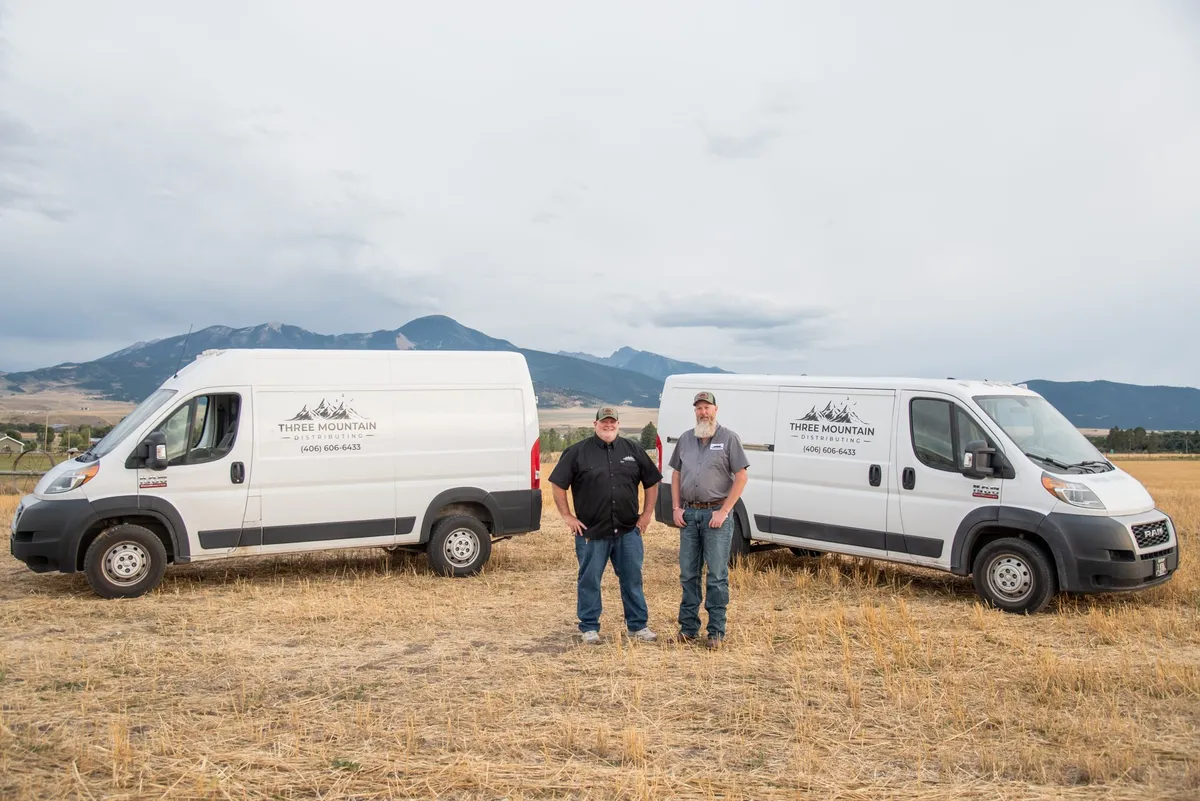 Three mountain distributing team standing by their van