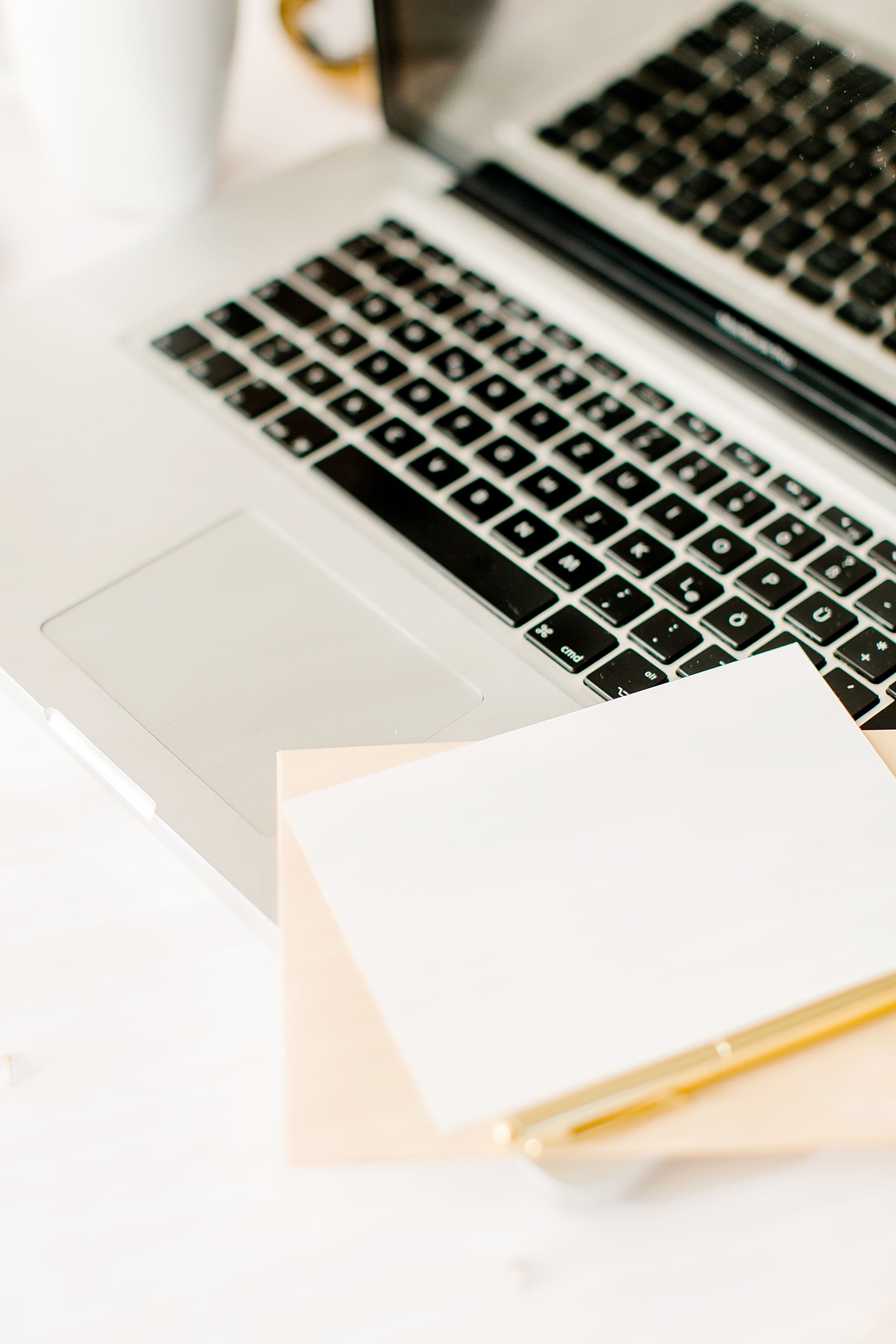 silberner Laptop, Notizblätter und goldener Stift