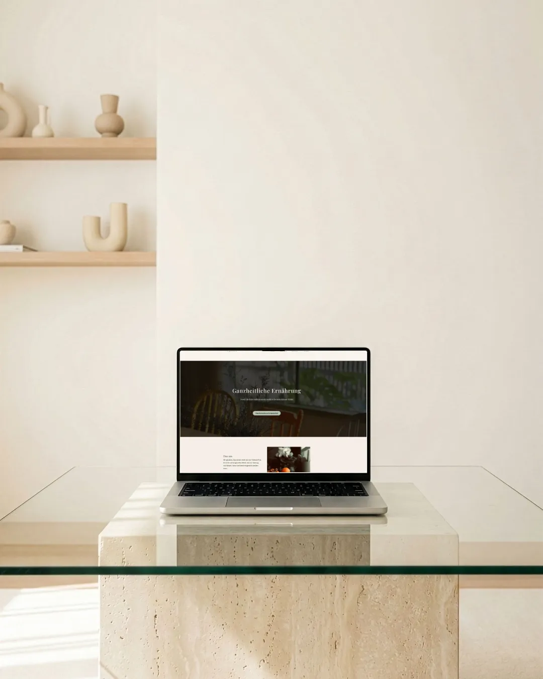 Laptop auf verschnörkeltem Tisch, Kaffeetasse + Sonnenbrille. Pflanzen im Hintergrund