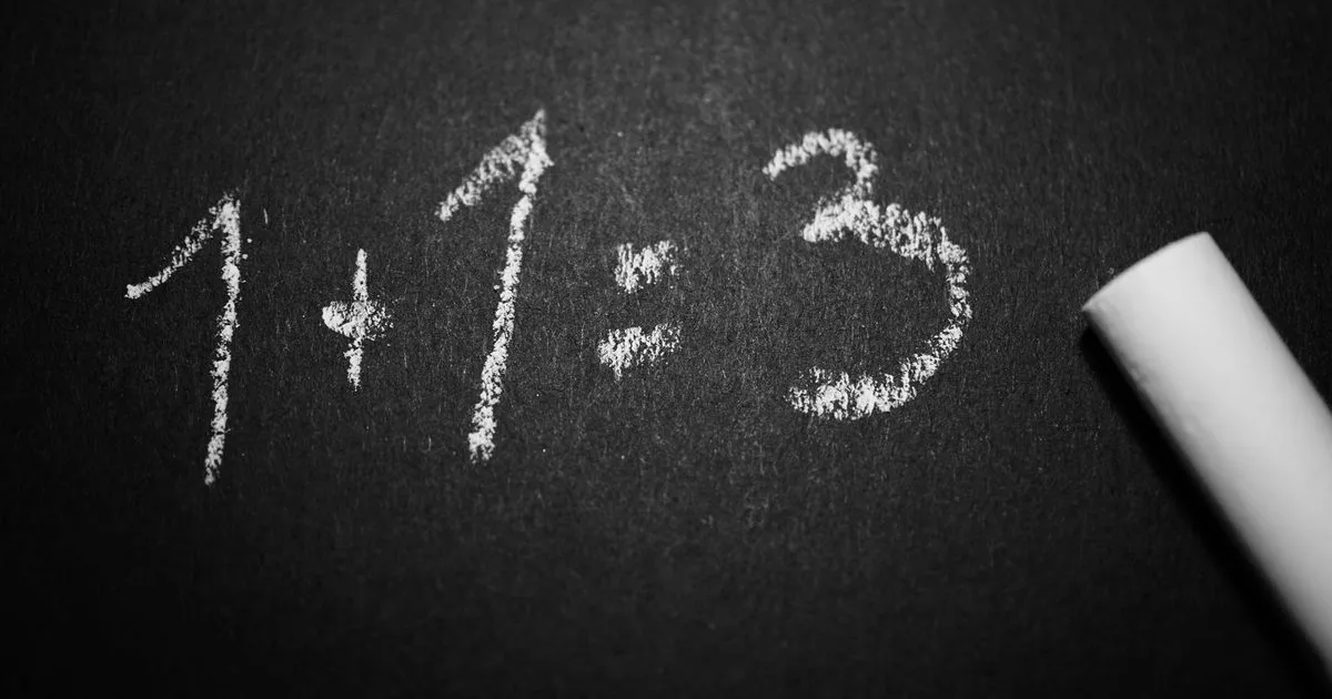 1+1=3 written in chalk on a blackboard