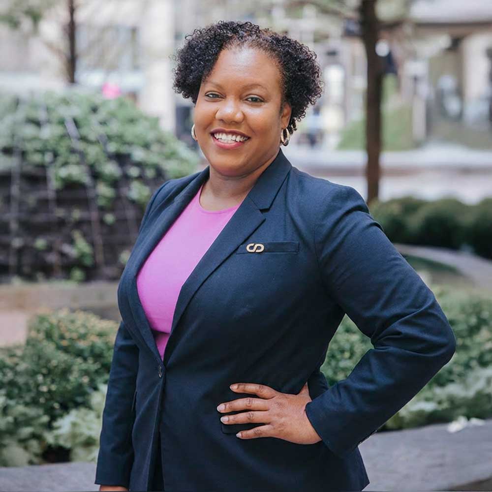 Coach Dora Mendez, HR consultant and leadership advisor, smiling outdoors in professional business attire.