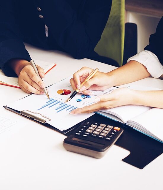 Hands working over financial paperwork with a calculator