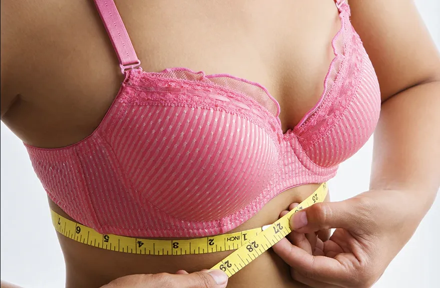 Woman in pink bra grasping measuring tap