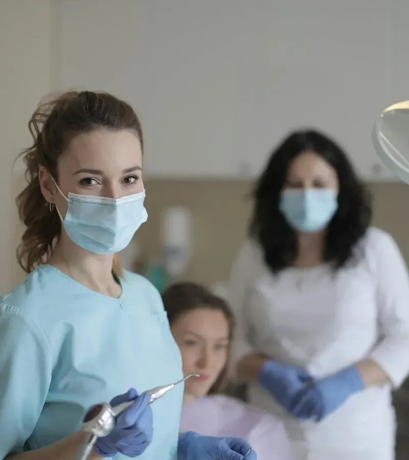 Two orthodontic professionals in a clinic, one holding dental equipment.