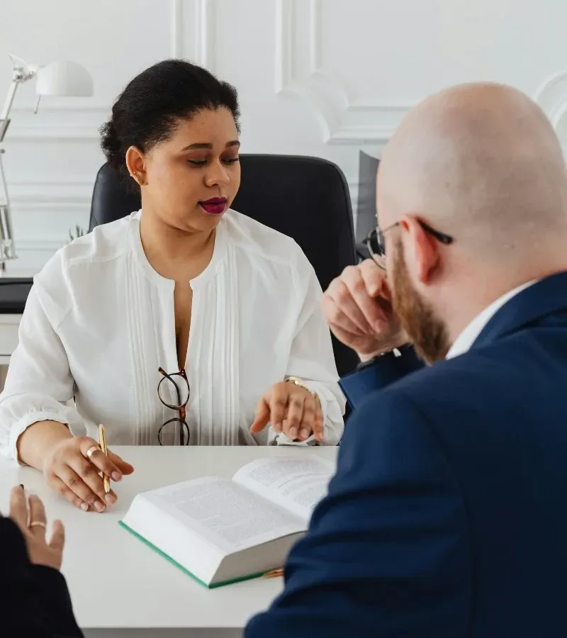 Orthodontist and patient discussing treatment plan, woman pointing to a book while the man listens.
