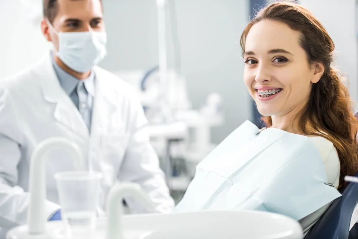 Smiling Orthodontic Patient with braces sitting in Ortho Office.
