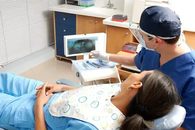 Orthodontist shows a dental X-ray to a patient in a chair.