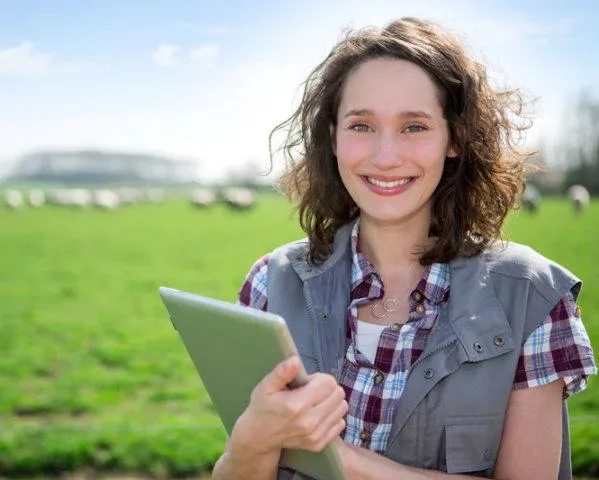 woman holding a laptop in a farm paddock