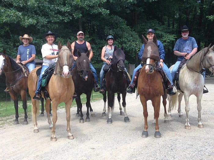 Riders on horseback along a wooded trail at Brighton Recreation Area