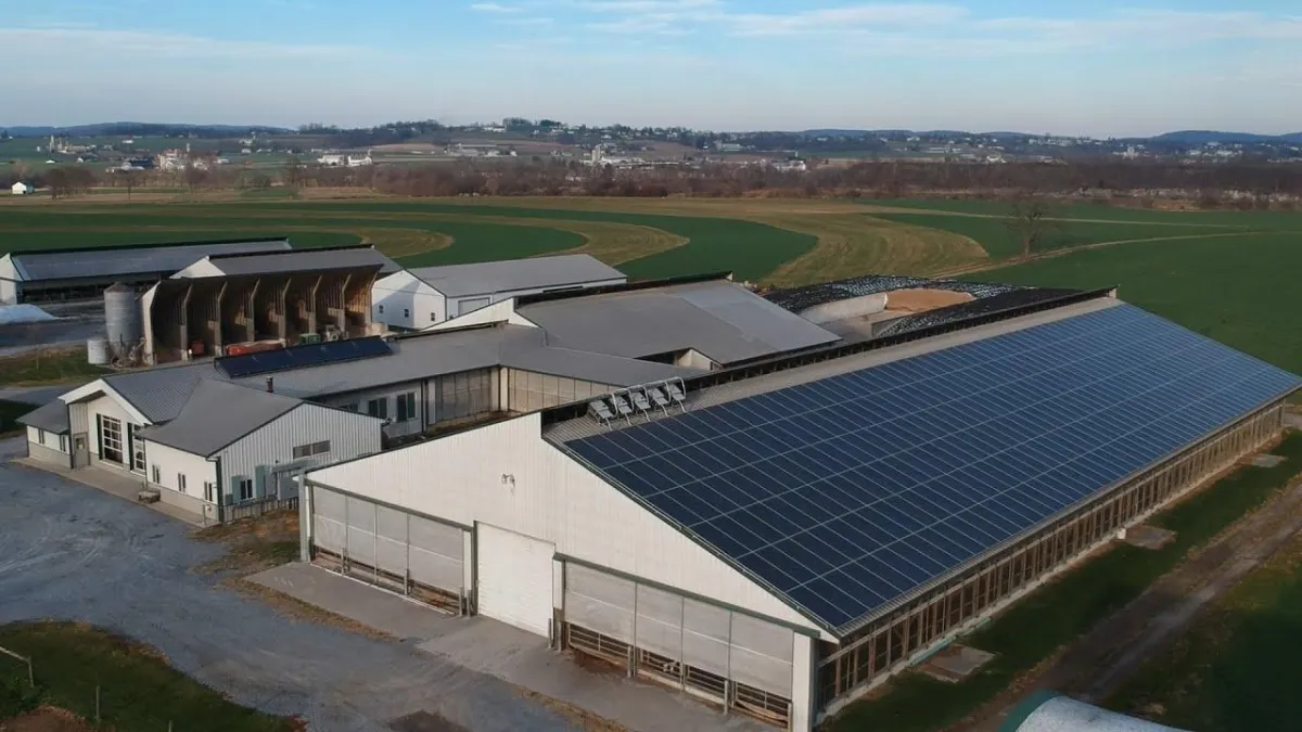 An aerial view of a modern NJ farm facility with large solar panels installed on the rooftops showcases an innovative solar solution.