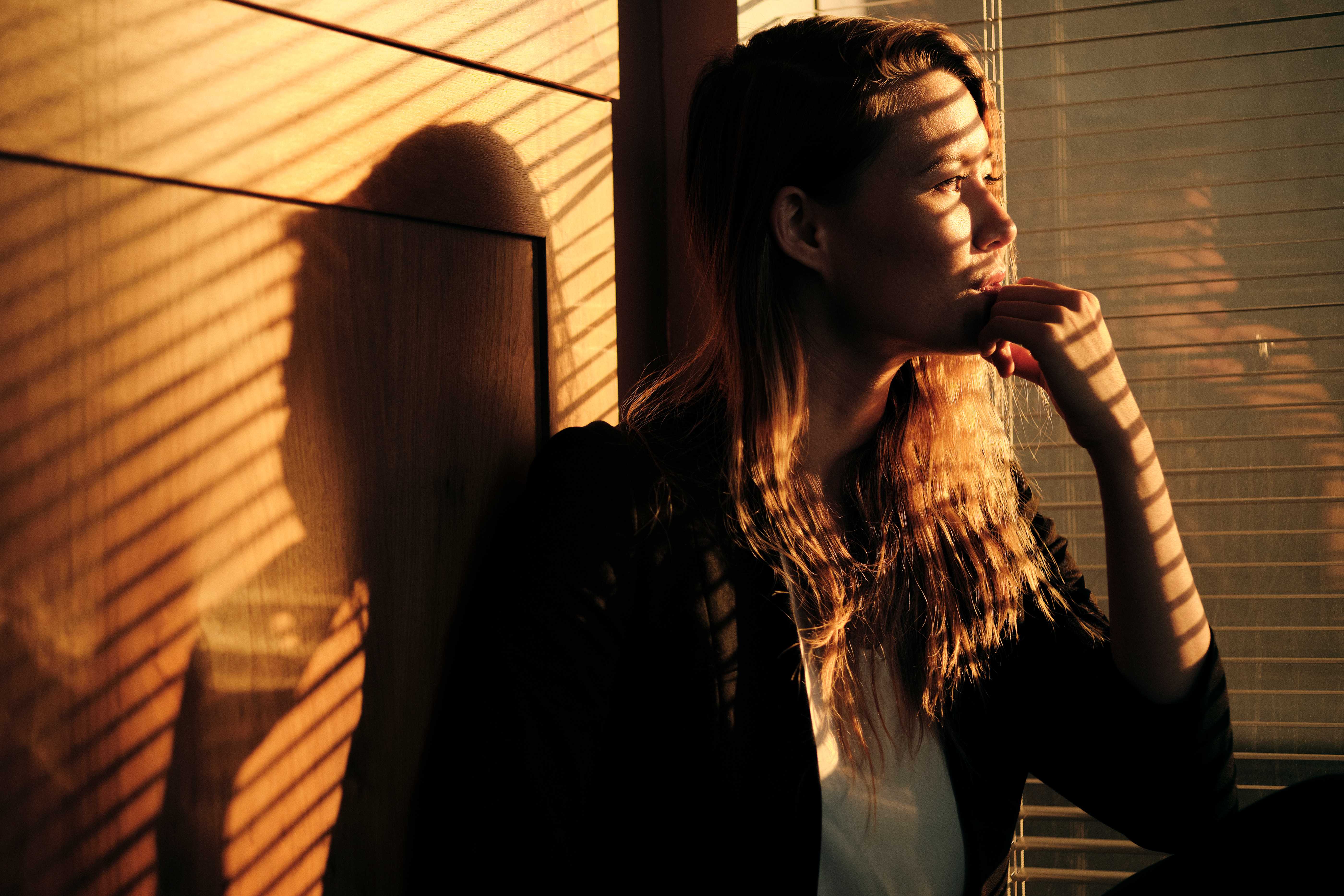 Woman sitting by a window in morning light, reflecting on life patterns and personal change
