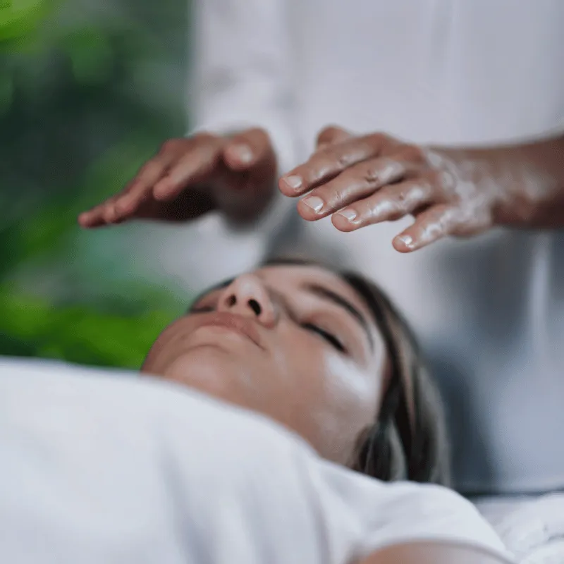 A person holding their hands open above a woman lying down