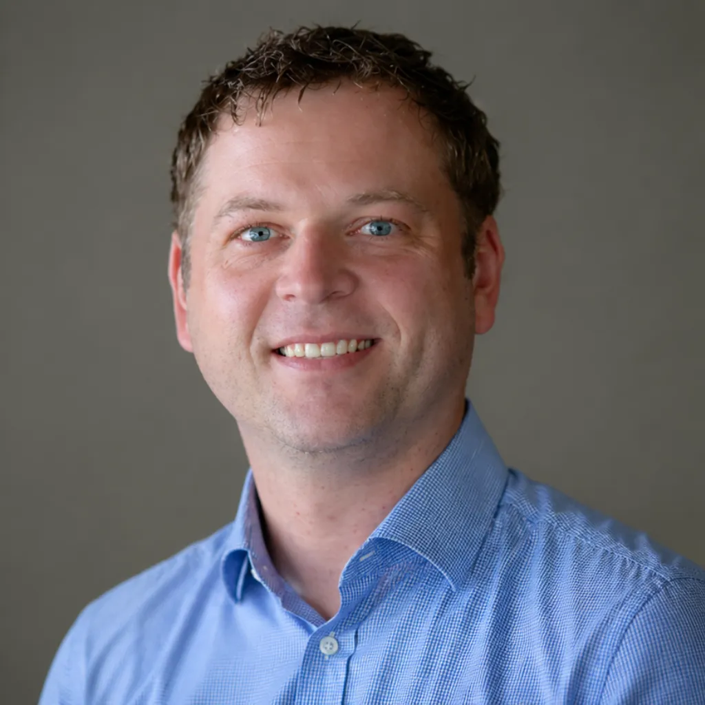 Smiling professional man in a blue shirt, representing career coaching and personal development for APS professionals in Canberra.