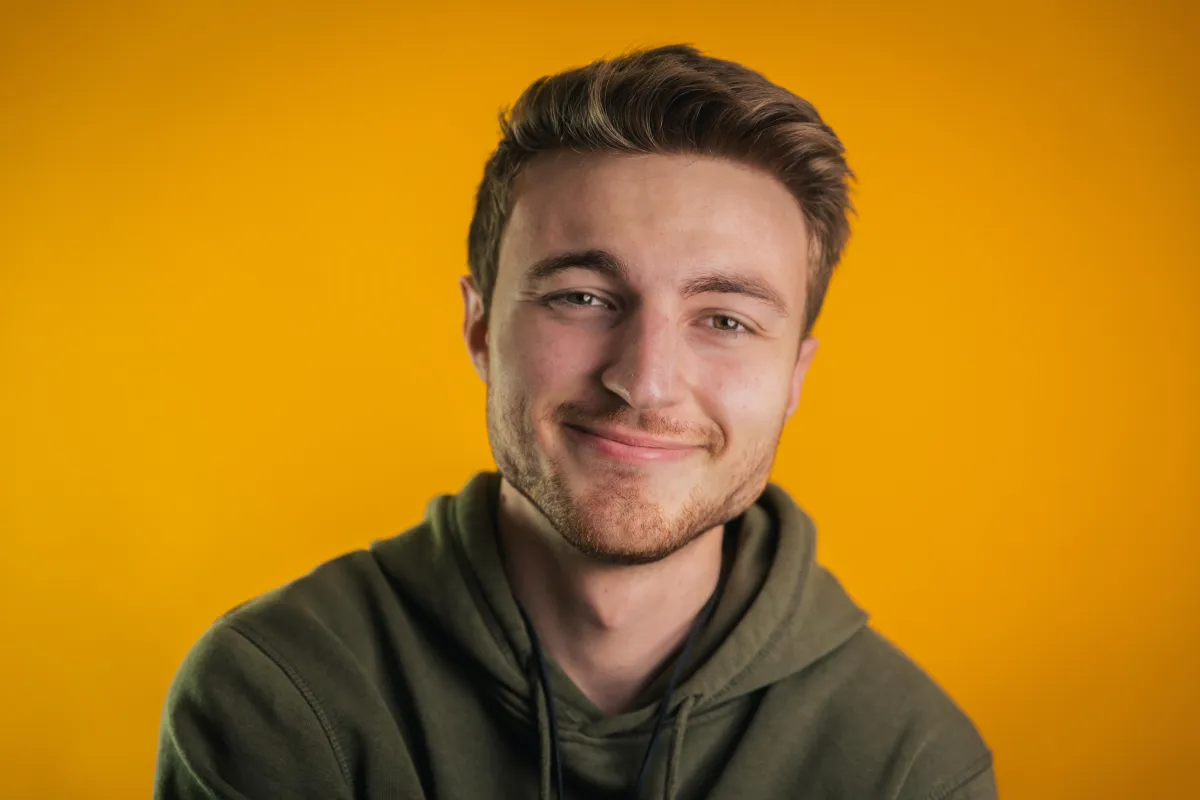 Tobias Katlein smiling in front of an orange backdrop