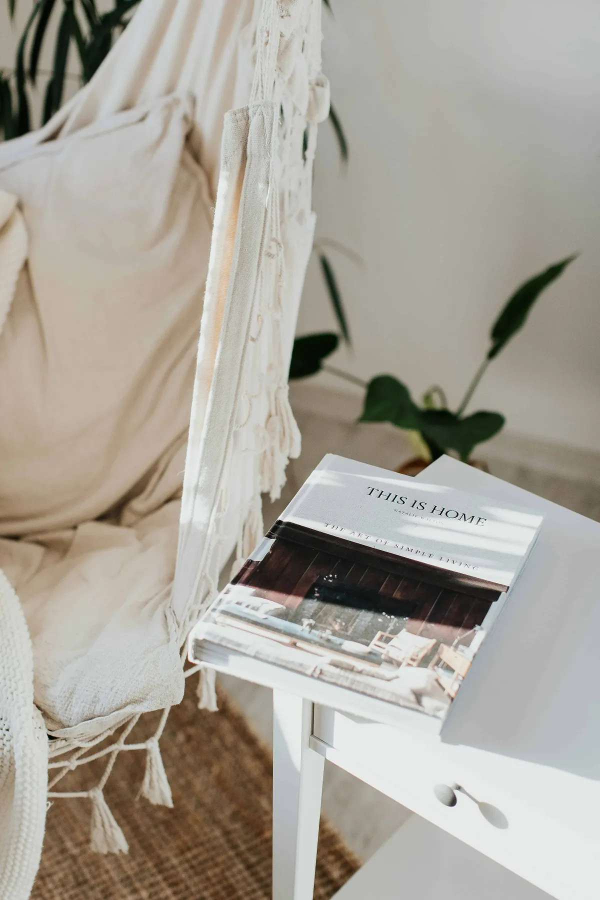 Boho ceiling swing with a white end table with a home decorating book