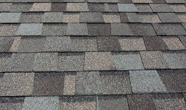 Close-up of high-quality architectural asphalt shingles in a weathered wood color.
