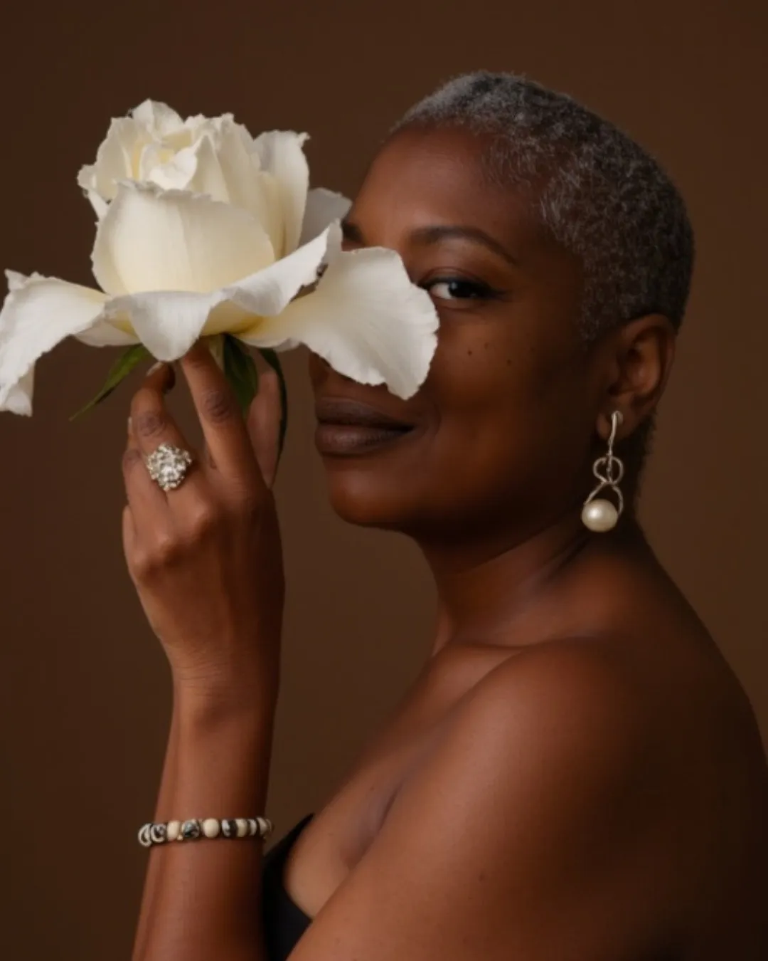 Tash Kain holding a white rose to her face