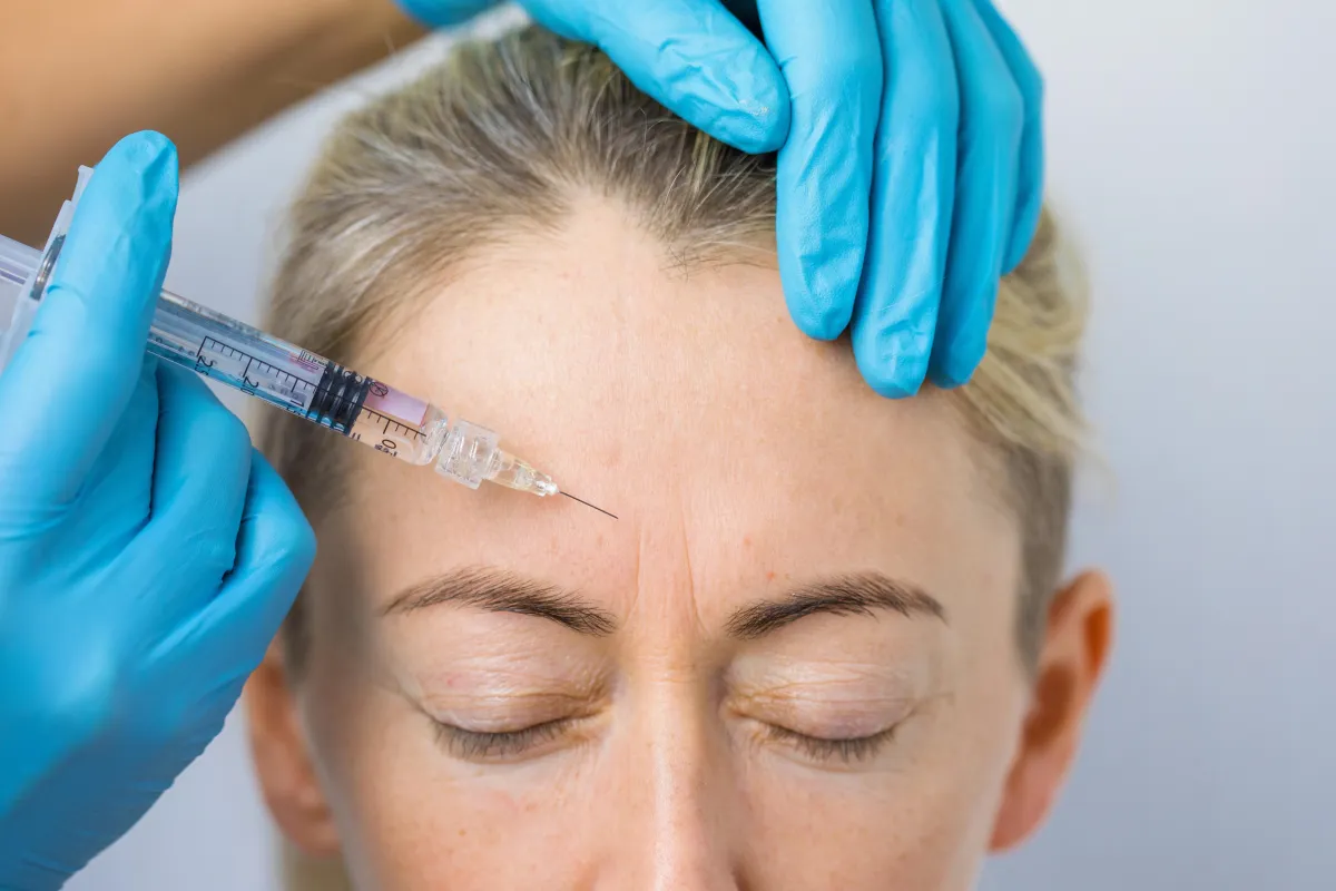 woman receiving an injection to her forehead to treat fine lines and wrinkles