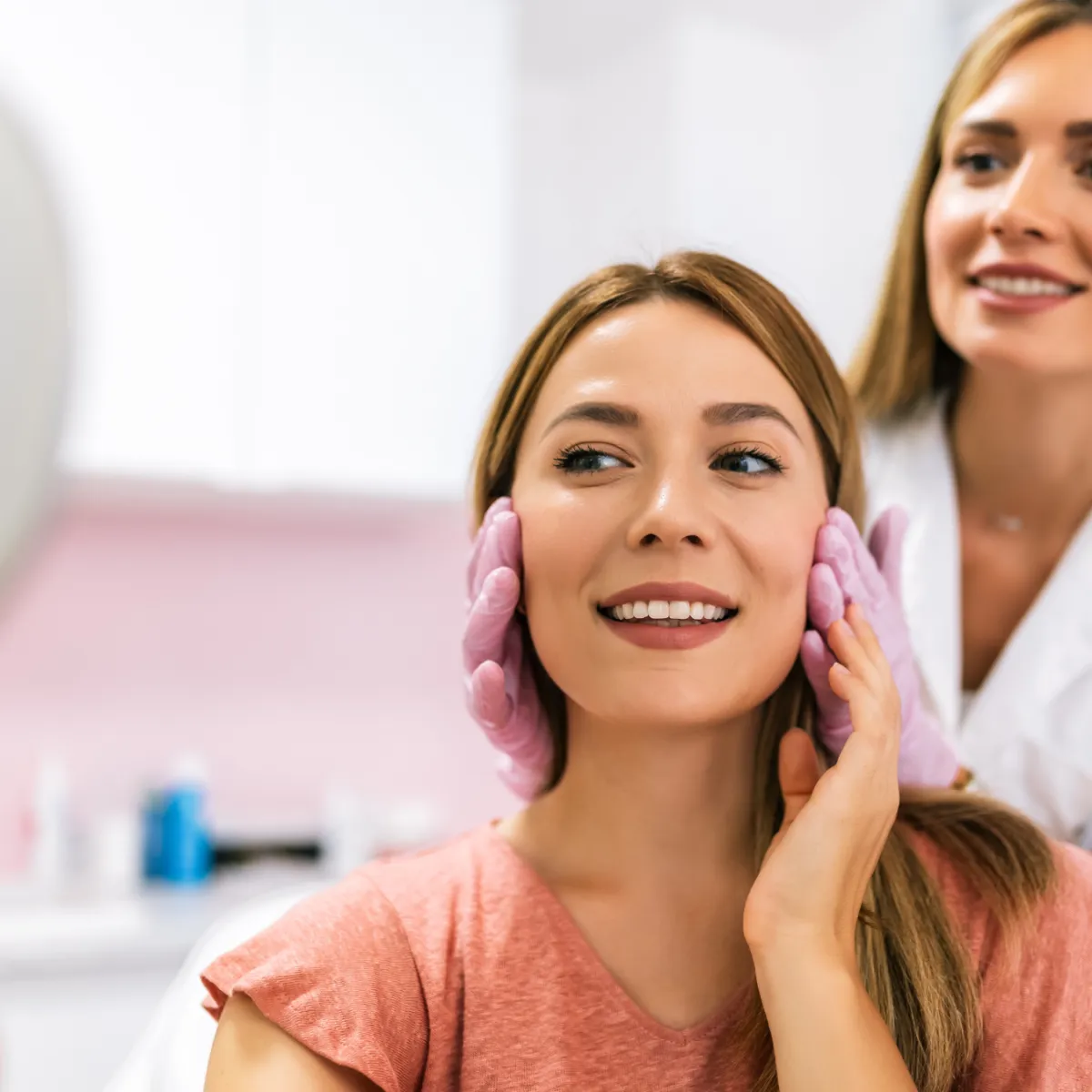 female aesthetician consulting her female paticent while placing her gloved hands on the sides of her face