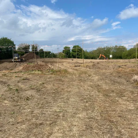 some levelled soil with a digger and dozer in distance