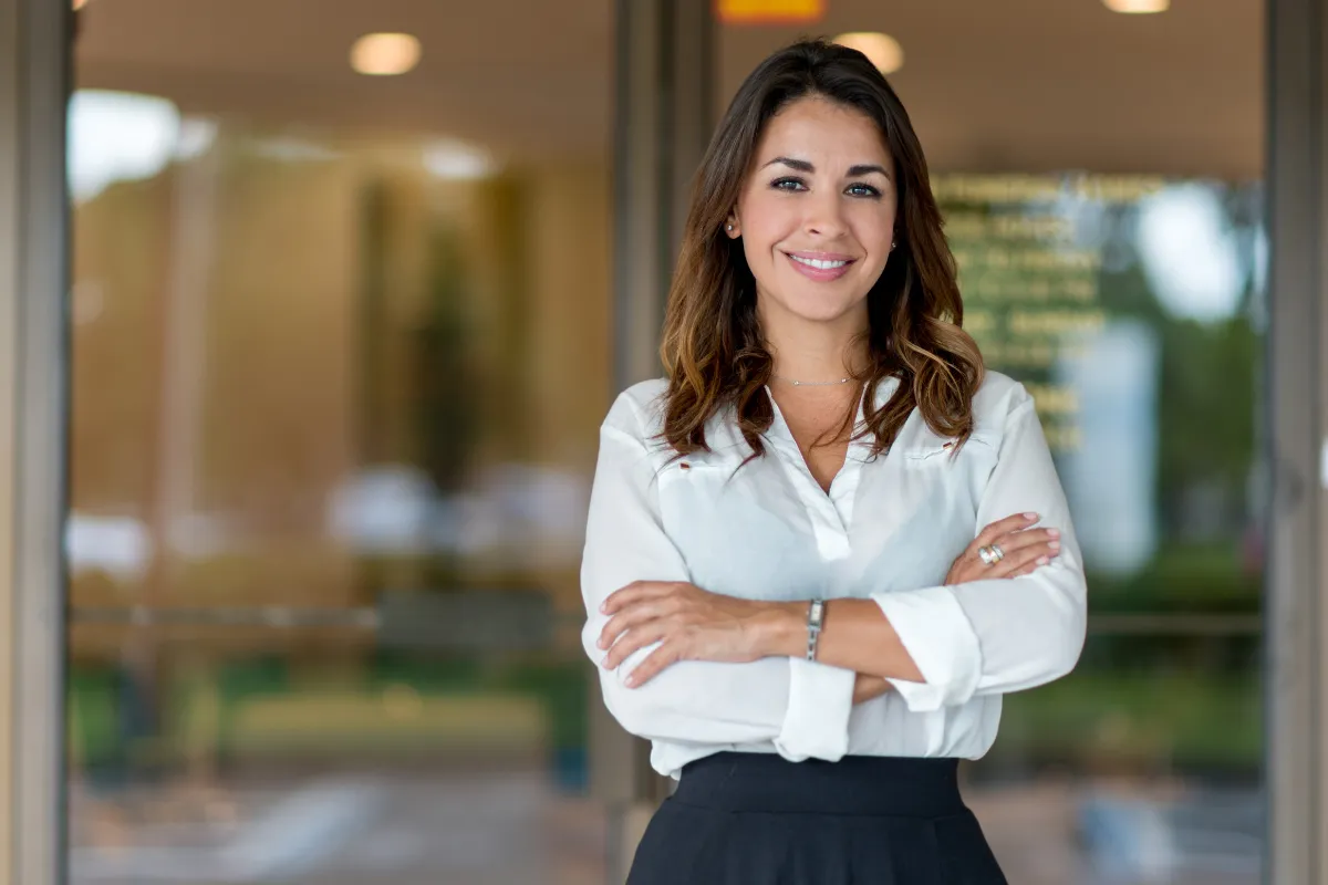 Confident female tax strategist and financial advisor standing with arms crossed outside an office building