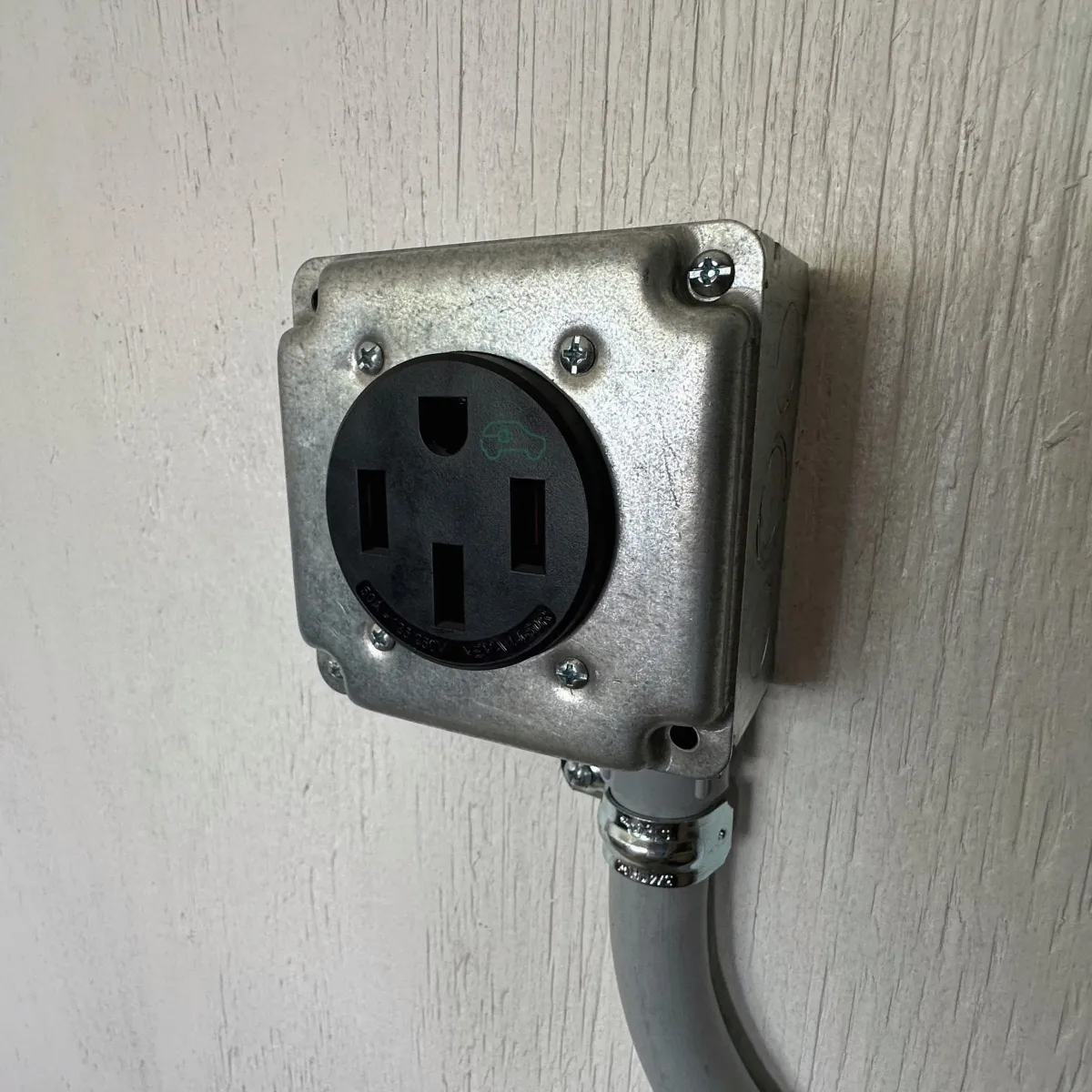 EV charging outlet installed on wall, featuring a black socket with car symbol, emphasizing home electric vehicle charging solutions for homeowners in Upstate SC.