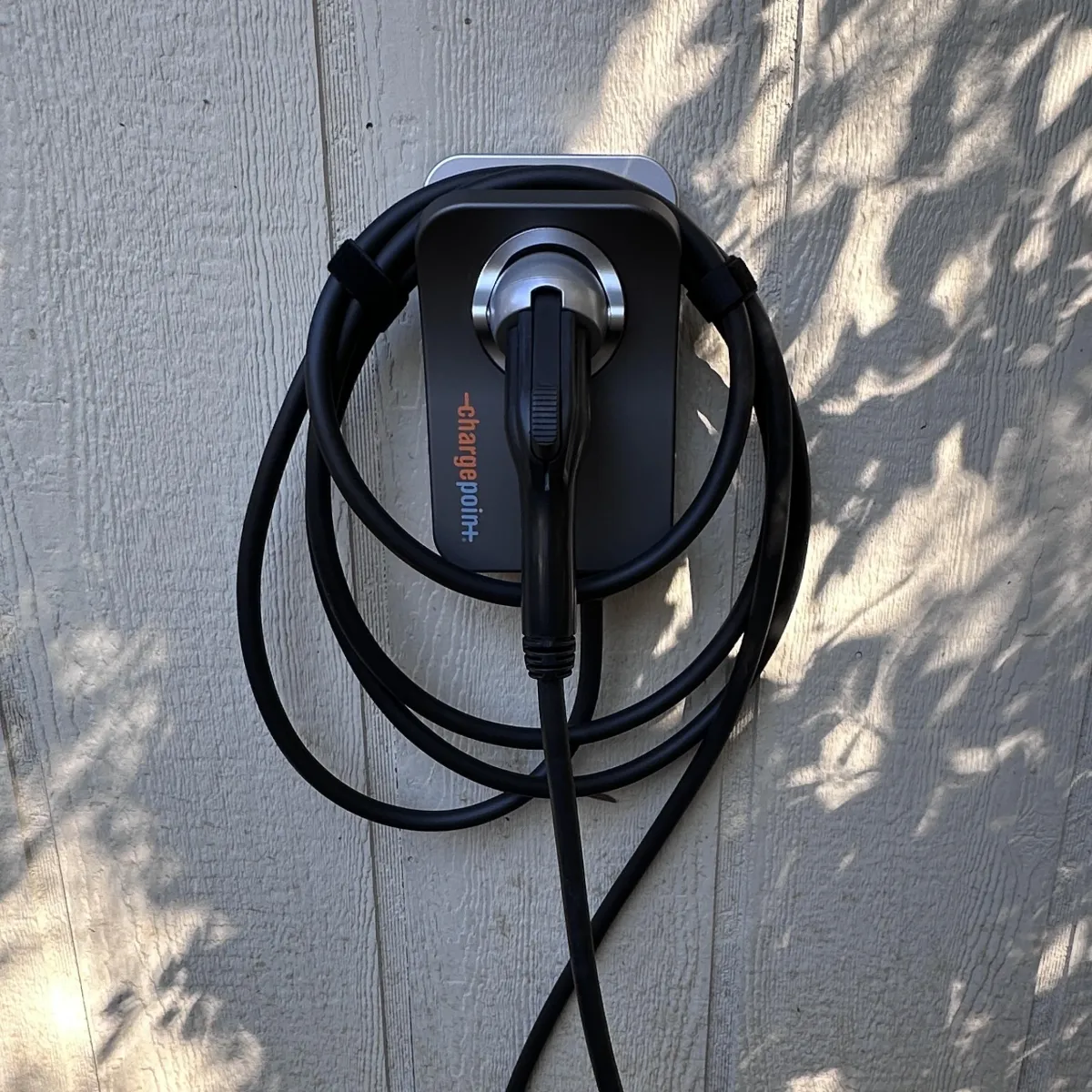 Electric vehicle charging station mounted on a wall, featuring a ChargePoint connector with coiled cables, emphasizing home EV charging solutions for Upstate homeowners.