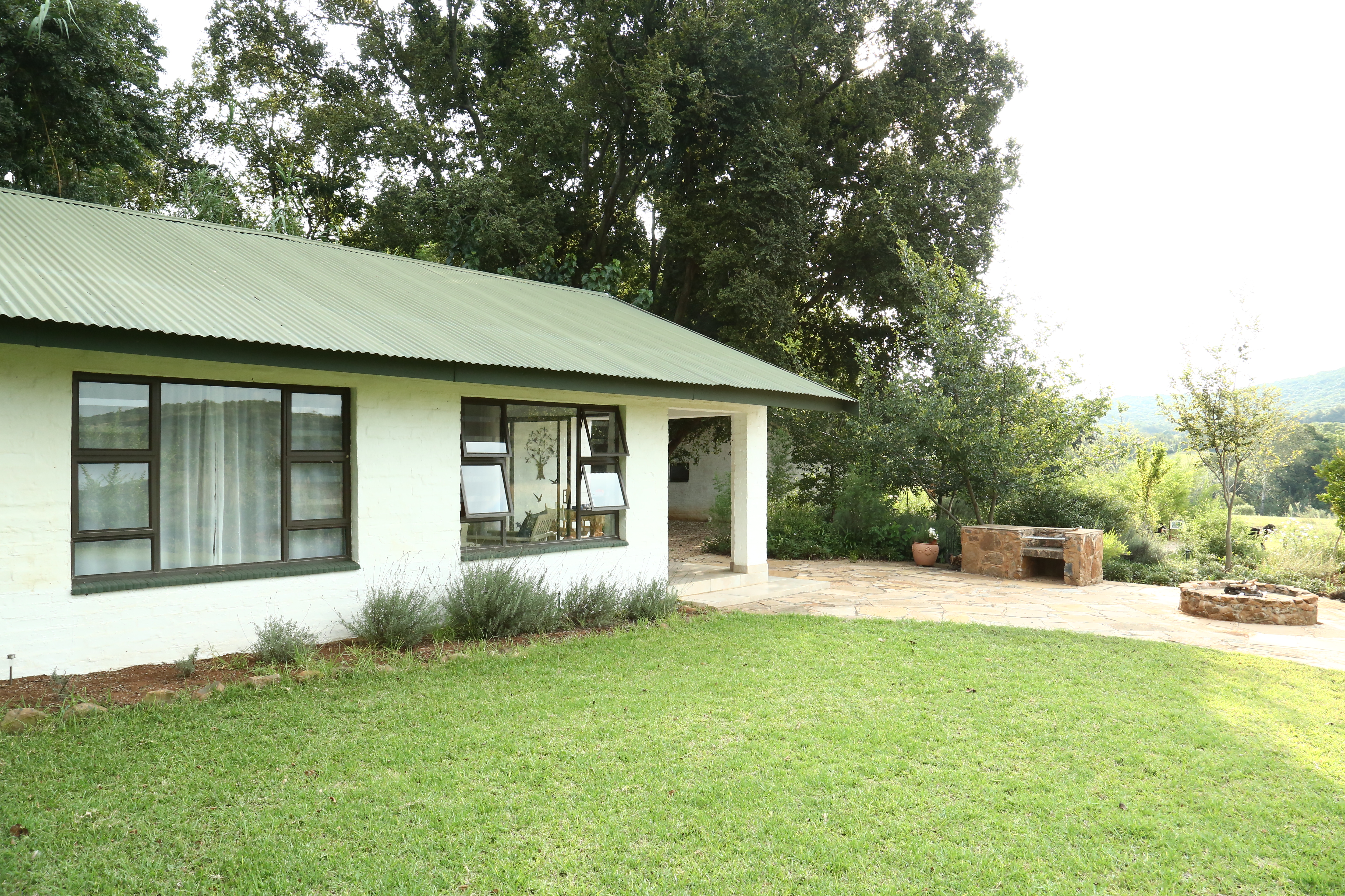 Exterior view of Bushwillow Cottage at Oude Doornbosch, showcasing its intimate, eco-friendly design surrounded by lush greenery.