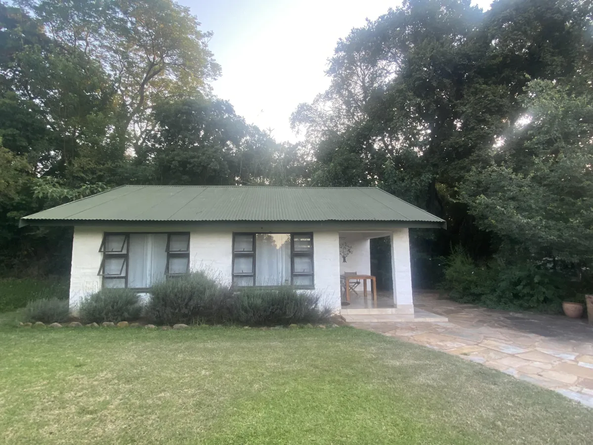Front view of Bushwillow Cottage at Oude Doornbosch with lush greenery and a serene environment.