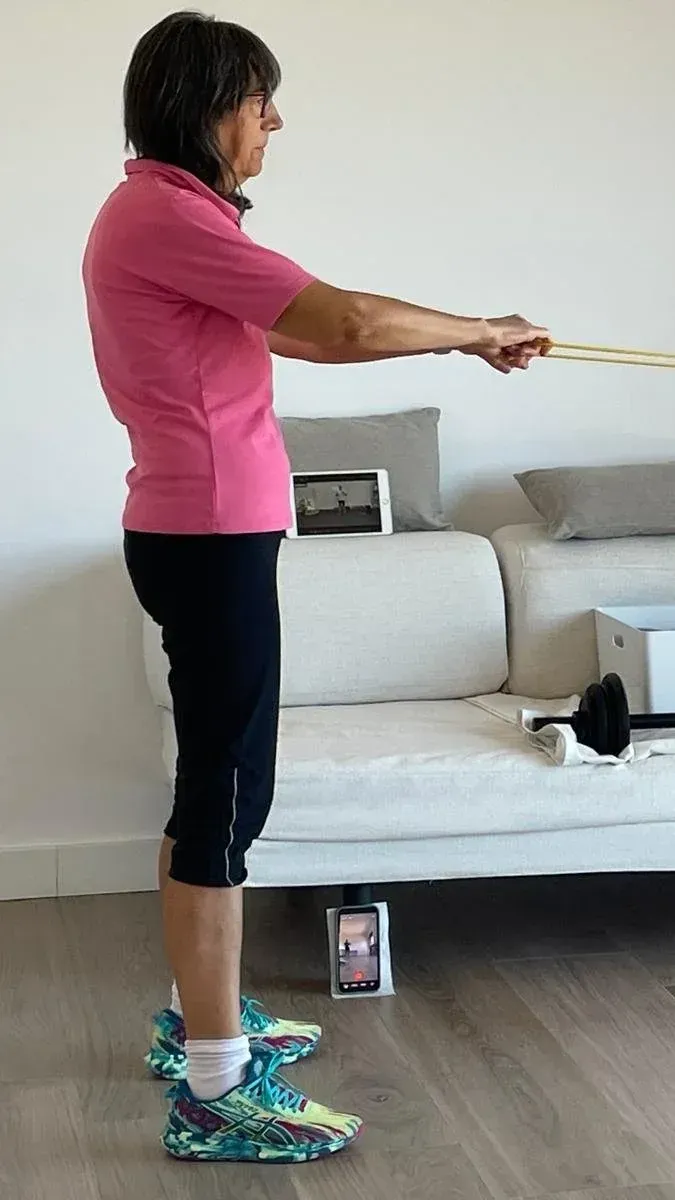 Alumna del programa entrenando con goma elástica en el salón de su casa