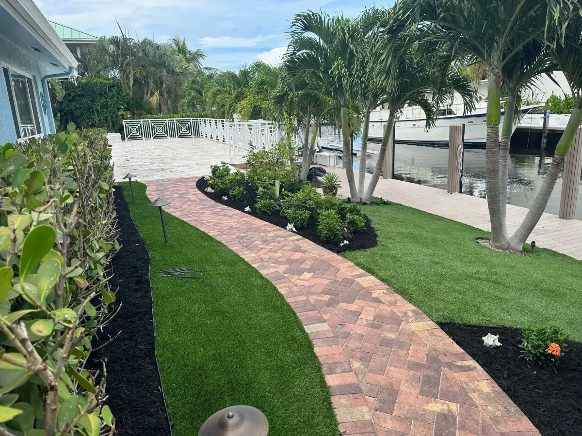 Brick paver driveway with landscaped hedges in Deerfield Beach – Quality Lawncare