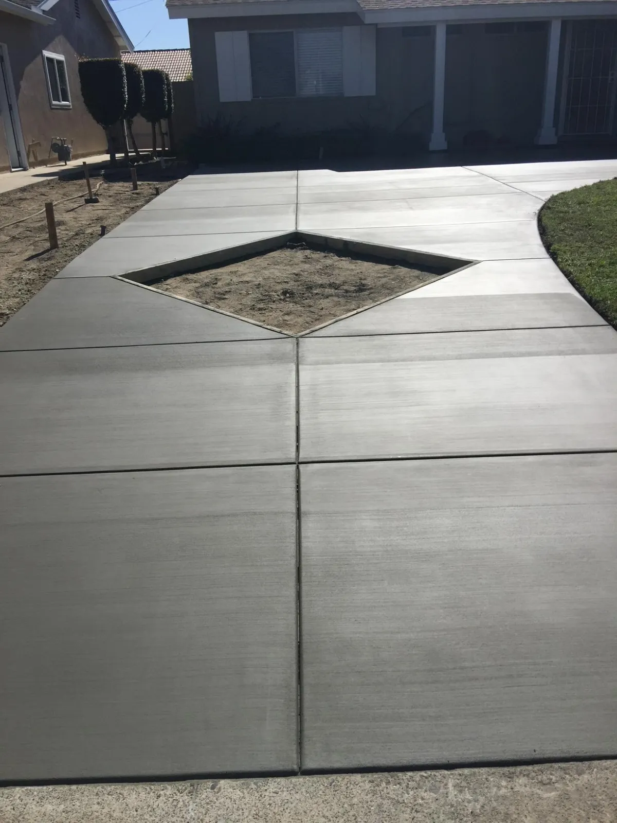 Freshly poured concrete driveway with square empty in center to fill with grass.