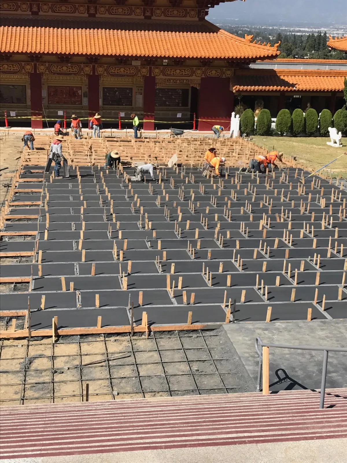 Concrete finisher working on a large slab of separated concrete squares.