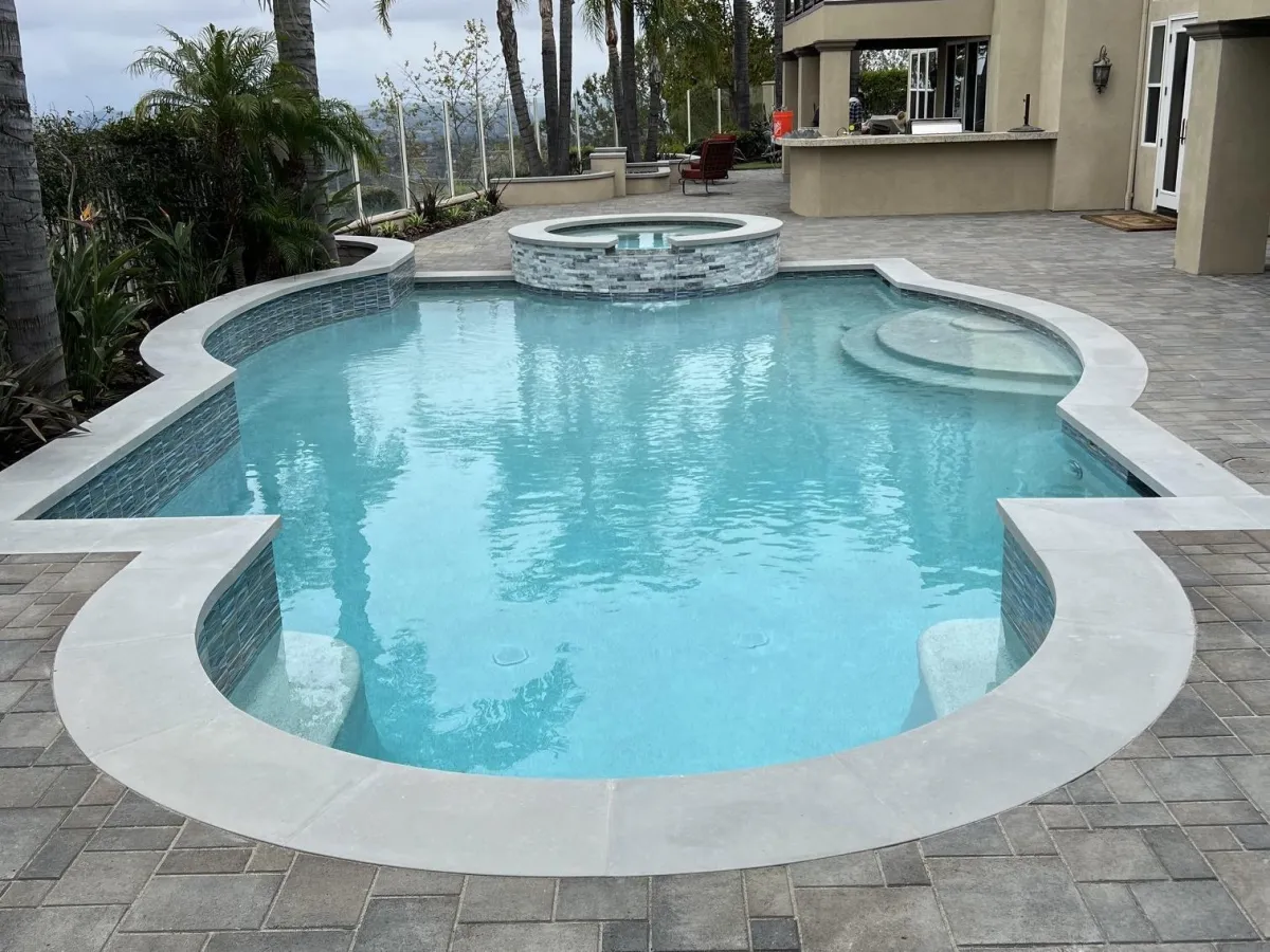 Backyard featuring a pool with colored coping surrounded by interlocking pavers.s