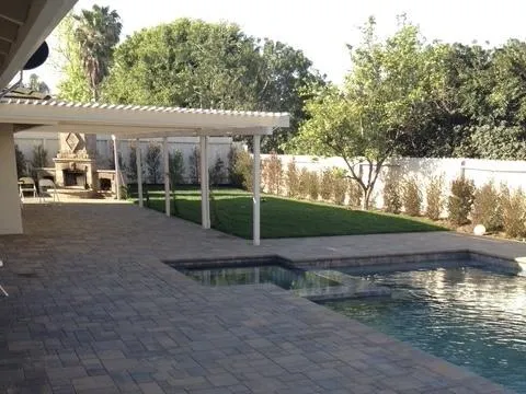 Backyard featuring a pool surrounded by interlocking pavers to the very edge of the pool.