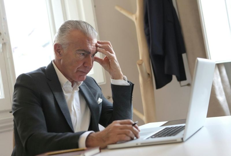 An elderly male busy on his laptop