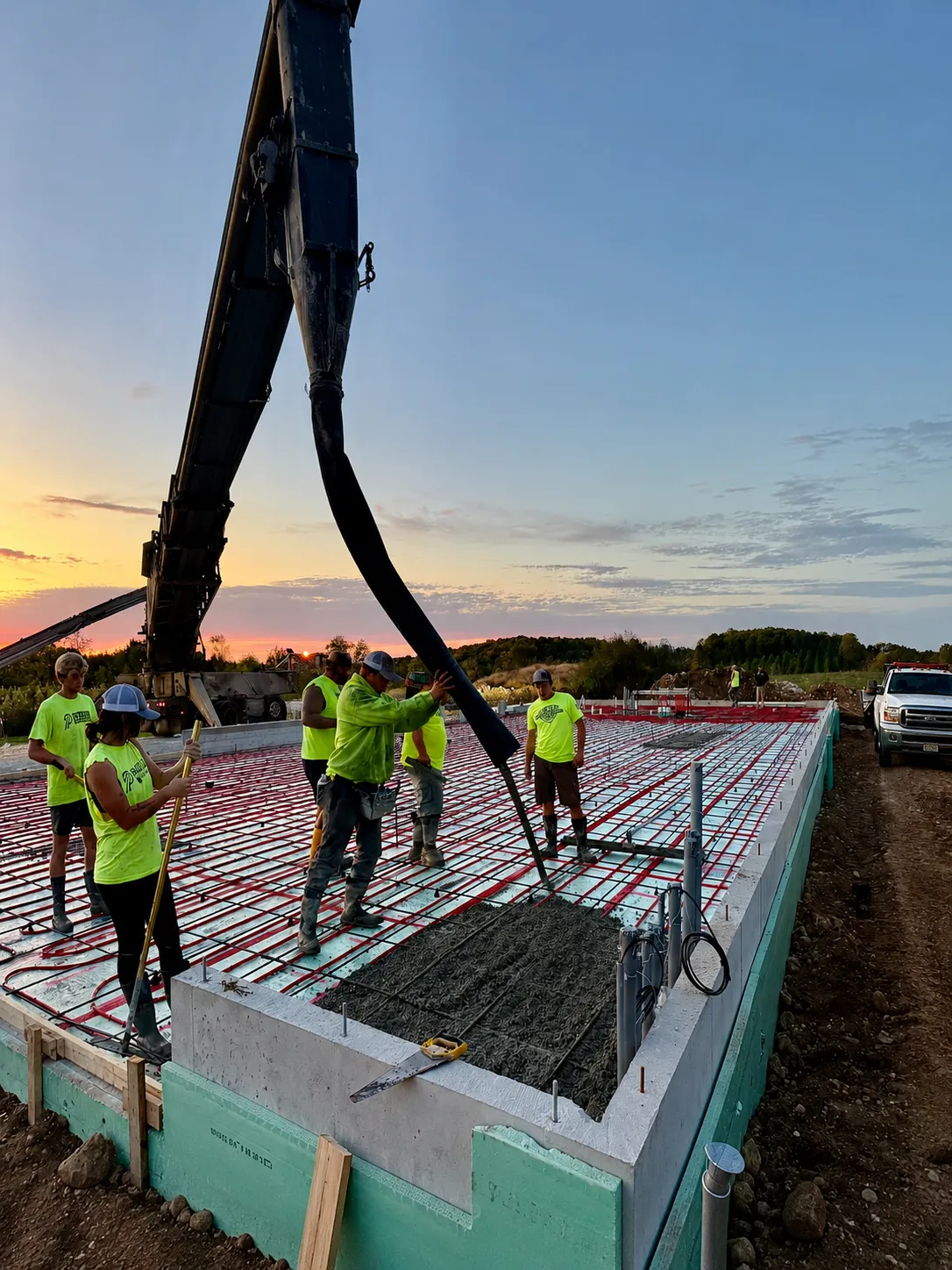 Concrete crew pumping and placing concrete over reinforcing steel for a large reinforced concrete slab.